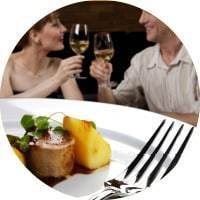 A restaurant scene focused on a plate of food with a couple enjoying a glass of wine in the background