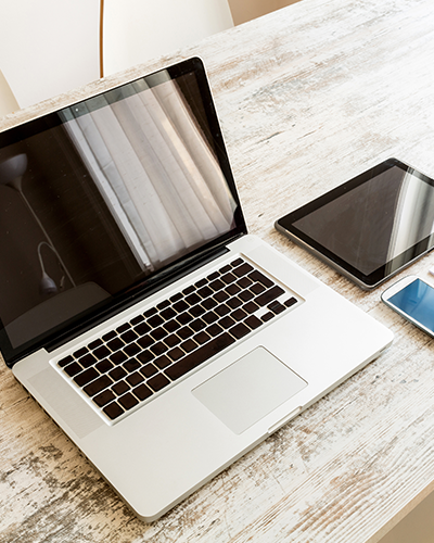 Laptop, tablet and telephone on a wooden desk