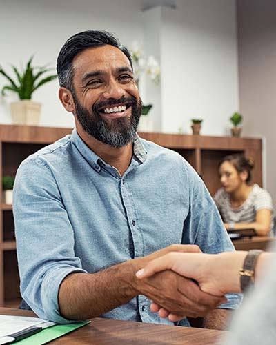 Smiling man shakes hands with someone out of frame