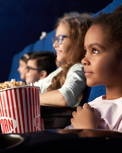 Young girls with popcorn in a cinema watching a movie