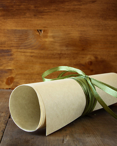 Timber background with paper scroll tied with green ribbon