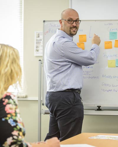 Consultant Andrew Ellis writing on the white board in front of clients