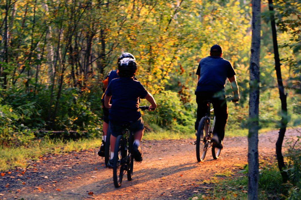 a man and two boys riding bikes through a forest