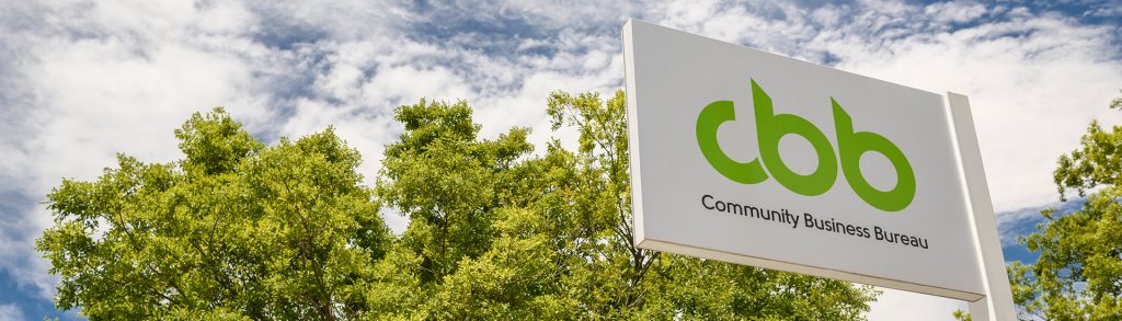 CBB signage outside head office, against a blue sky and green tree line