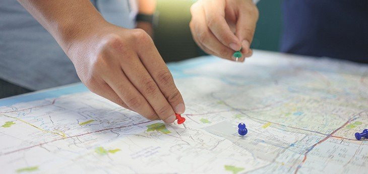 two people placing pins on a map