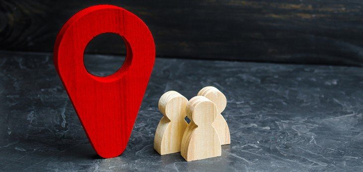 An image of three wooden figures next to a red marker