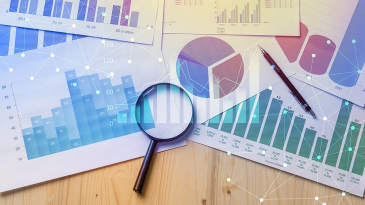 Magnifying glass on top of paper displaying different types of graphs