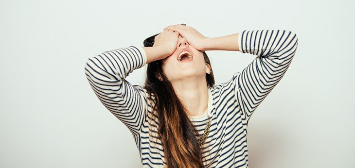 A woman with her head held back and hands covering her face