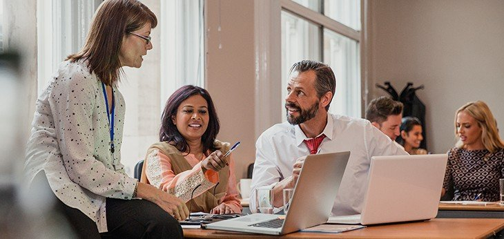 three people sitting around a table working together