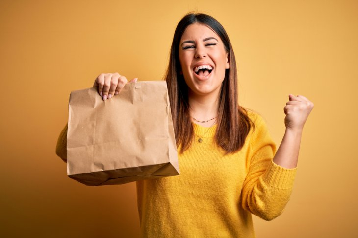 Woman holding a bag of takeaway food and cheering