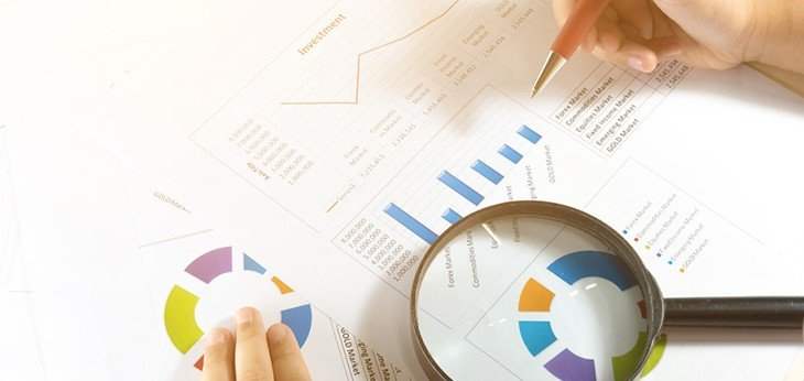 a person working on financial charts with a magnifying glass highlighting one chart