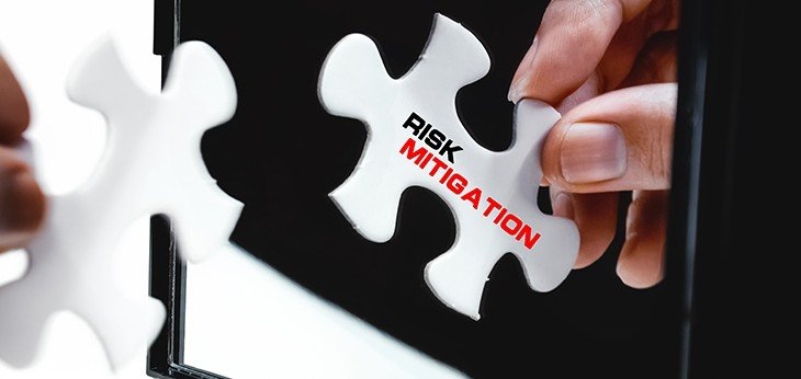 White jigsaw puzzle piece with Riskk Mitigation written on it being held in front of a mirror