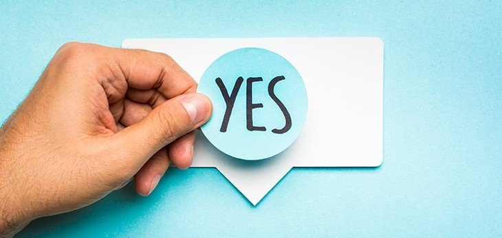 A hand placing a yes sticker on a speech bubble